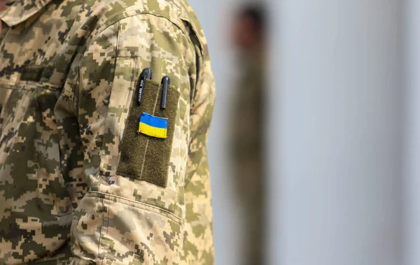 POLTAVA, UKRAINE  18 MAY, 2022: Ukrainian flag in the uniform of the Ukrainian military