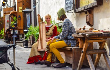 TALLINN, ESTONIA - 14 Ağustos 2018: Etnik kostümlü sokak müzisyenleri yaz öğleden sonra bir bankta oturuyorlar