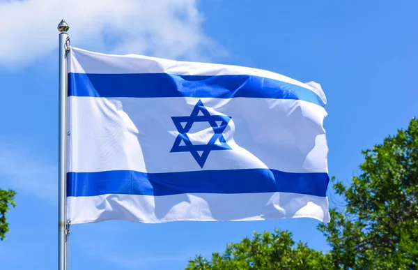 イスラエルの旗は白い長方形の布で 端には水平方向の青い縞模様が2本 中央にはダビデの星が夏の午後に青い空に向かって描かれています — ストック写真