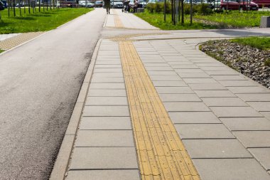 Yaz günü asfalt yolda engelli insanlar için dokunulabilir fayanslar.