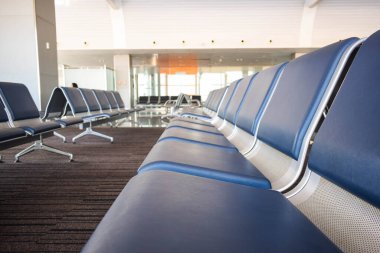 Havaalanının bekleme odasında oturuyor.