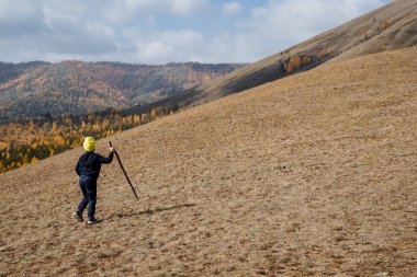 Parlak sarı şapkalı küçük bir çocuk özel bastonlarıyla dağda yürür ve ormana bakar. Tüm aileyle dağlara seyahat, aktif eğlence, kaya tırmanışı. Yüksek kalite fotoğraf