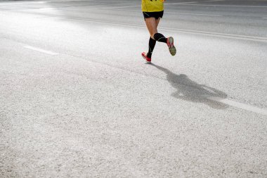 Koşan bir adamın bacaklarına yakın çekim. Aktif eğlence, spor ve futbol oynamak. Parlak spor üniforması ve ayakkabılar. Atletik fiziği ve güçlü bacak kasları. Yüksek kalite fotoğraf