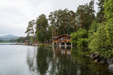 Sessiz gölün panoramik manzarası ve sudaki ahşap ev. Açık hava eğlencesi. Yüksek kalite fotoğraf