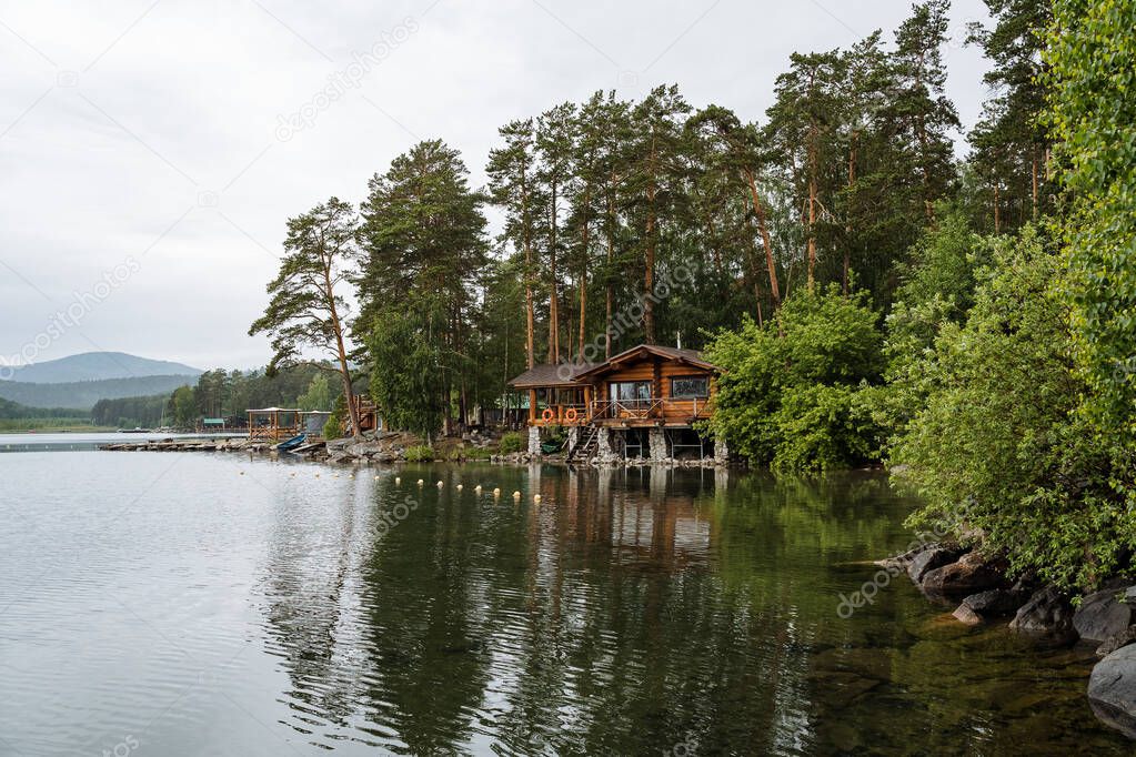 Panoramic view of the quiet lake and wooden house right by the water. Outdoor recreation. High quality photo