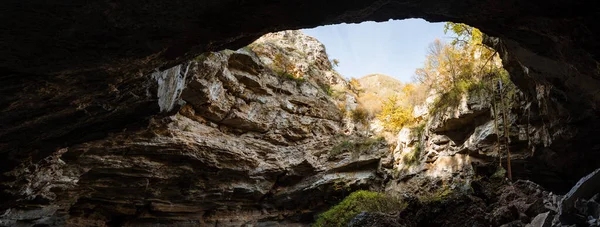 Panoramic view of the exit from the cave. sunlight penetrates and illuminates the exit from the cave, the walls are covered with green moss. Exploring caves and wildlife. High quality photo — Stock Photo, Image
