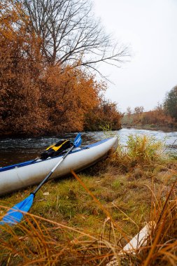 Şişme tekne bir dağ nehrinin kıyısında duruyor. Su yolculuğu için mavi kano. Bulutlu havada sonbahar tekne gezisi. Güney Urallar 'da, Rusya' da, Bashkortostan 'da turizm. Yüksek kalite fotoğraf