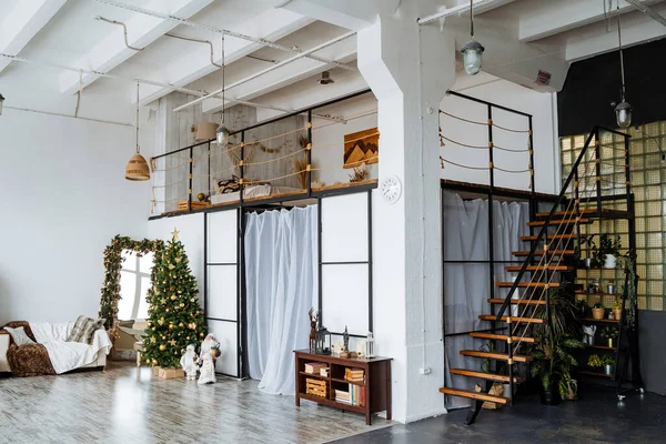 Disparo interior. Escaleras de metal negro al segundo piso, una estela con plantas verdes, árbol de Navidad decorado, preparativos para el nuevo año Modernos apartmen —  Fotos de Stock