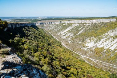 Yazın dağ manzarası. Parlak, sert orman. Dağlarda aktif dinlenme, uçsuz bucaksız genişlikler, açık mavi gökyüzü. Dağlar arasındaki yol.