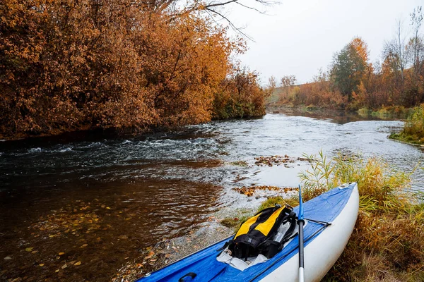Le bateau gonflable se trouve sur la rive d'une rivière de montagne. Kayak bleu pour le voyage en eau. Excursion en bateau en automne par temps nuageux. Tourisme dans le sud de l'Oural, Russie, Bachkortostan — Photo