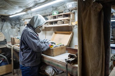 Marangoz atölyesinde. Testere seçiyorum. Ahşap işleme ve oyma. Özel üniforma ve gaz maskesi. Marangozların işyeri