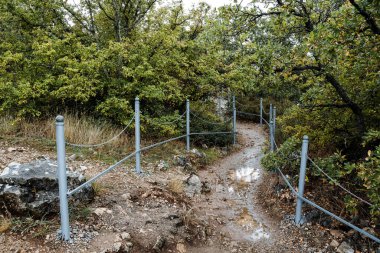 Dağlarda çitlerle çevrili küçük bir patika. Dağlarda yürüyün, temiz havada dinlenin. Kayalık böbrek, iflas etmiş yol.