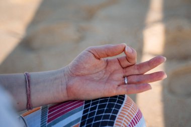 Bir elin yakın çekimi meditasyon pozunda katlanır. Deniz kıyısında meditasyon ve yoga. Huzur, huzur ve uyum arayışı. Sahilde rahatla. Yüksek kalite fotoğraf