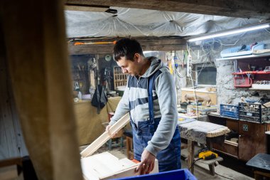 El işi. Bir marangoz atölyede ahşap işliyor. Tahta ürünler. Ahşap oyma aletleri. Katılımcı tahtayı parlatır.
