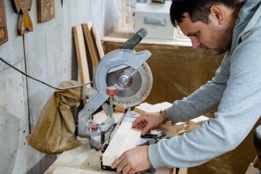 Marangoz ahşap bir barı testereyle kesiyor. El işi. Ahşap işleme. Testerenin yakın çekimi. Testere tahtaları için kurulum. Marangozluk atölyesinde ekipman