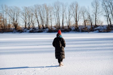 Genç bir kız donmuş bir gölde yürüyor. Kışın gölün panoramik manzarası. Parlak soğuk güneş. Kışın doğa yürüyüşü. Yüksek kalite fotoğraf