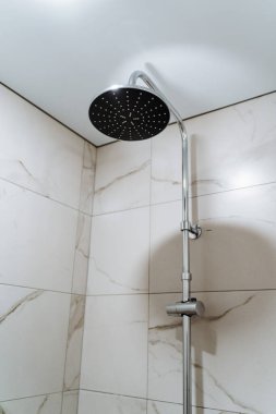 Büyük yuvarlak sulama kutusuyla duş rafı. Mermer duvarlı banyo. Rahatça duş alıyorum. Minimalist modern iç mimari. Yüksek kalite fotoğraf