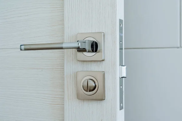 Metal kapı kolu. Modern bir iç mekanda beyaz ahşap kapı. Odanın girişi. Evin minimalist iç mekanı. Yüksek kalite fotoğraf