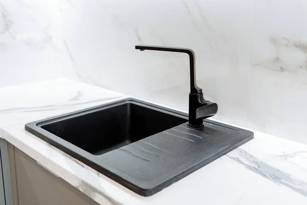 Siyah minimalist mutfak lavabosu. Mutfak modern bir dairede. Lavabo yapay, doğal taştan yapılmış. Minimalist iç çekim. Yüksek kalite fotoğraf