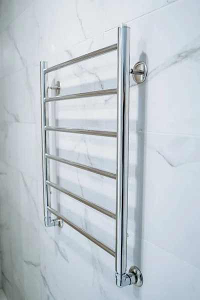 Väggmonterad handdukstork i duschrummet. Marmor vita väggar i badrummet. Metalluppvärmd handdukshängare. Modernt rum. — Stockfoto