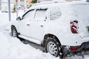 The car is buried under a layer of snow. Heavy snowfall in the city. The equipment stands under a snowdrift. Consequences of a winter hurricane. High quality photo