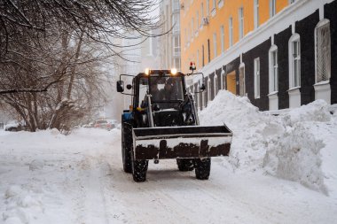 A tractor cleans snow in the city. Clearing the street of snow after a snowstorm. Ufa Russia. Clean streets. Winter in the city. High quality photo