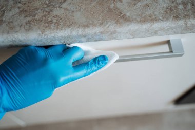 Mikroplara karşı bir yöntemle yüzeyin dezenfekte edilmesi. Eldivenli bir el antiseptik bir bezle kutuların yüzeyini siler. Mutfağı temizliyorum. Kapı koluna bak.