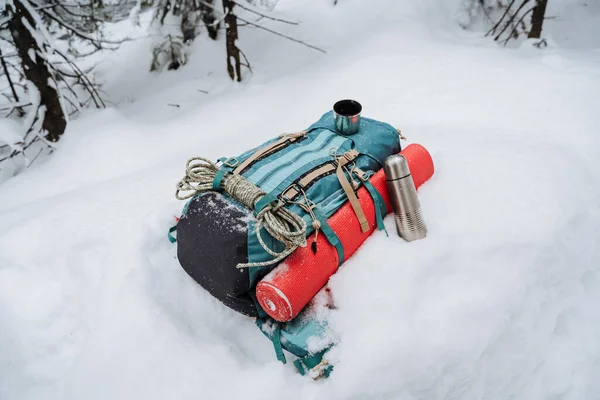 雪の上にはキャンプ用具付きのバックパックがあります 山の中で冬のハイキング 登山のための機器 紅茶と魔法瓶 高品質の写真 — ストック写真