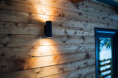 Çift ışıklı parlak sokak lambası. Evin yakınındaki caddelerde ışıklandırma. Evin ahşap duvarları. Yüksek kalite ve iyi inşaat ve onarım