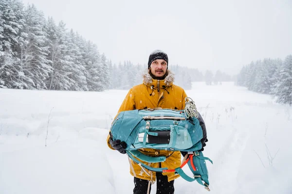 幸せな旅行者は彼の手にリュックを持っている 雪の森と岩と明るいハイキングバックパック 冬には山に登る 野生での生存 高品質の写真 — ストック写真