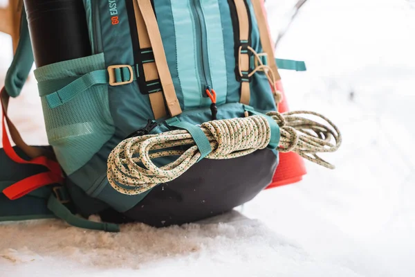 雪の上には明るいハイキングバックパックがあります 登山用ロープはリュックに縛られています 魔法瓶のサイドポケットに 冬のハイキング 岩や森 高品質の写真 — ストック写真