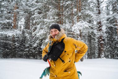 Gülümseyen ve kemer çantalı mutlu bir gezgin. Karlı orman ve kayalar. Kışın dağa tırmanmak. Vahşi doğada hayatta kalmak. Yüksek kalite fotoğraf