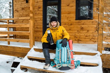 Gülümseyen ve mutlu gezgin termostan sıcak çay ya da kahve içecek. Kışın dağa tırmanmak. Vahşi doğada hayatta kalmak. Yüksek kalite fotoğraf