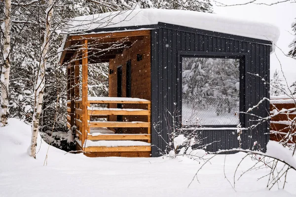 Modular house made of dark metal and light wood in winter forest. a house that takes into account everything you need for a comfortable life outside the city. High quality photo