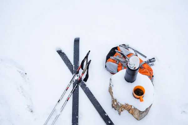 雪の上に偽りの棒とスキーがある魔法瓶とオレンジのハイキングバックパックと紅茶のマグカップの横に 冬はまだ雪の中で生活 森の中でスキー 新鮮な空気 高品質の写真 — ストック写真
