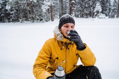 Gülümseyen ve mutlu gezgin termostan sıcak çay ya da kahve içer. Kışın dağa tırmanmak. Vahşi doğada hayatta kalmak. Yüksek kalite fotoğraf