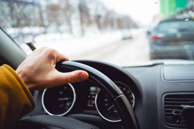 Bir adamın eli arabanın direksiyonunda. Şehrin etrafında dolaşıyordum. İletişim paneli, arabanın içi siyah, hız kontrol sistemi. Yüksek kalite fotoğraf