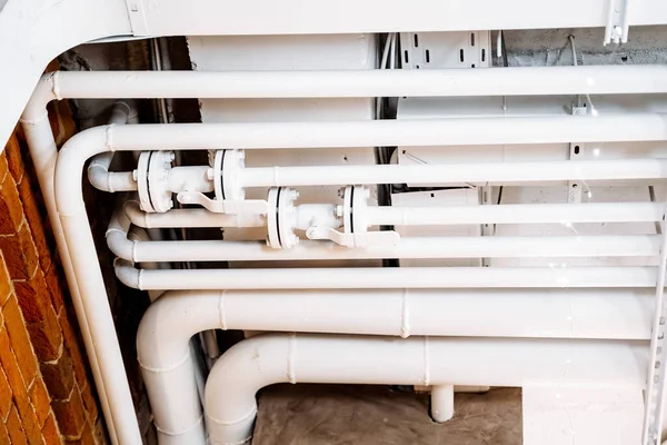 Tavandaki borular beyaz. Evin içinde kanalizasyon sistemi var. Metal ana tesisat musluğu. Gaz kapama vanası. Yüksek kalite fotoğraf