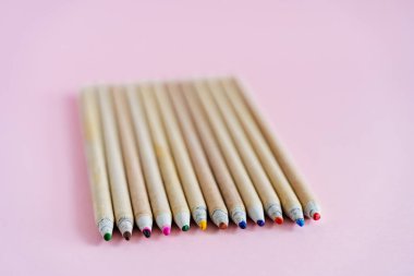 Pembe masanın üzerinde parlak renkli kalemler var. Çizim için bir set kalem. Çocuklarda yaratıcı yetenekler geliştirmek için. Doğal ahşaptan yapılmış kalemler. Yüksek kalite fotoğraf