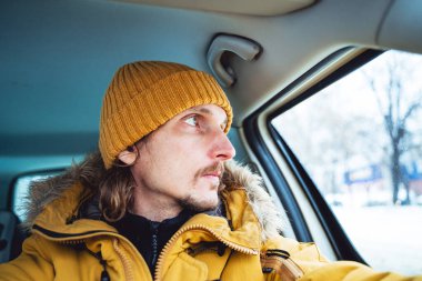 Düşünceli adam arabanın camından dışarı bakıyor. Adam dikiz aynasına bakıyor. Kışın araba kullanmak. Profilde bir portre. Yüksek kalite fotoğraf