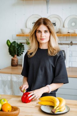 Salata için sebze doğrayan güzel bir kız. Mutfakta hoş bir sarışın. Parlak iç mekan. Akılda kalıcı bir bayan görünüşü, inanılmaz bir kadın güzelliği. Yüksek kalite fotoğraf