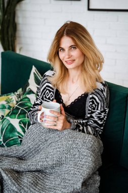 Şirin bir kız elinde battaniye ve bir kupa çayla oturuyor. Kendinle sıcak bir gün geçir. Huzur ve huzur içinde yat. Rahat ol. Yüksek kalite fotoğraf