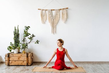 Kırmızı elbiseli bir bayan, yarı omurga kıvrımı pozu verir. Yoga egzersizi. Ardha Matsyendrasana. Kendinle olmanın zamanı geldi. Huzur ve hareket zamanı. Yüksek kalite fotoğraf