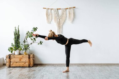 Kız parlak bir stüdyoda yoga yapıyor. Eğitmen Ağaç Pozu yapıyor. Vrikshasana. Dünyamızda huzuru ve huzuru bulmak için. Zen. Yüksek kalite fotoğraf