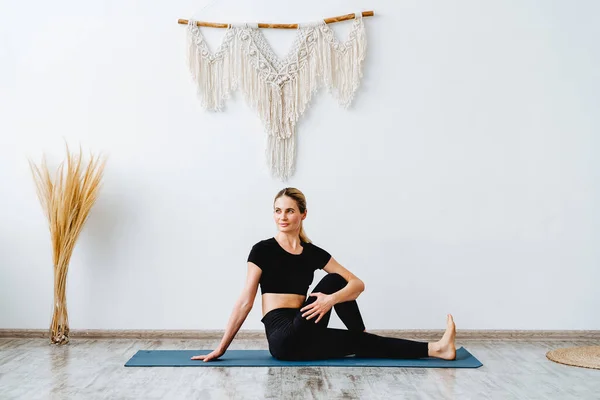 A relaxed young girl rests on a yoga mat.Perform assanas.Parivrtta Janu Sirsasana.Revolved Head-to-Knee.Peaceful atmosphere in a studio. — Stock Photo, Image