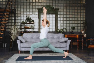 Yoga hocası evde alıştırma yapar. Güzel bir kız iyi bir savaşçı kılığına girer. 1.Virabhadasana. Yeni başlayanlar için Assanas. Nirvana