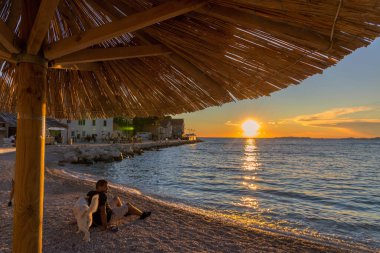 Primosten kasabası, Adriyatik Denizi ve Hırvatistan 'da plajda gün batımı