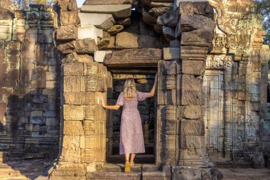 Angkor kompleksindeki Ta Prohm tapınağının yıkıntılarında ağaçlarla kaplı bir kız, Kamboçya
