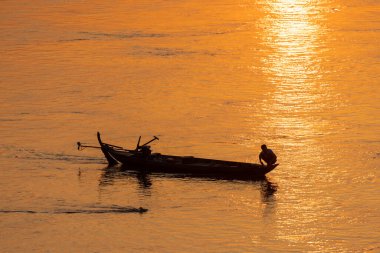 Fisherman on the traditional boat  on the Mekong River in Cambodia during sunset 