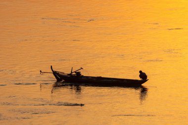 Kamboçya 'daki Mekong Nehri' nin geleneksel teknesinde gün batımında balıkçı. 